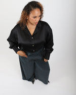 Load image into Gallery viewer, Woman wearing a black silk shirt and patterned pants on a white background