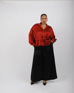 Load image into Gallery viewer, Person wearing a red silk blouse and black palazzo trousers on a white background