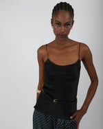 Load image into Gallery viewer, Woman wearing a black silk top with thin straps against a plain background, by Paradisefold