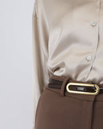 Load image into Gallery viewer, Close-up of a Paradisefold oyster silk shirt with a brown belt and gold buckle on a light gray background