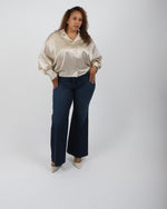 Load image into Gallery viewer, Paradisefold Woman wearing a oyster champagne silk shirt and dark jeans on a white background