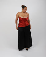 Load image into Gallery viewer, Woman wearing a red silk top and black skirt on a white background by Paradisefold