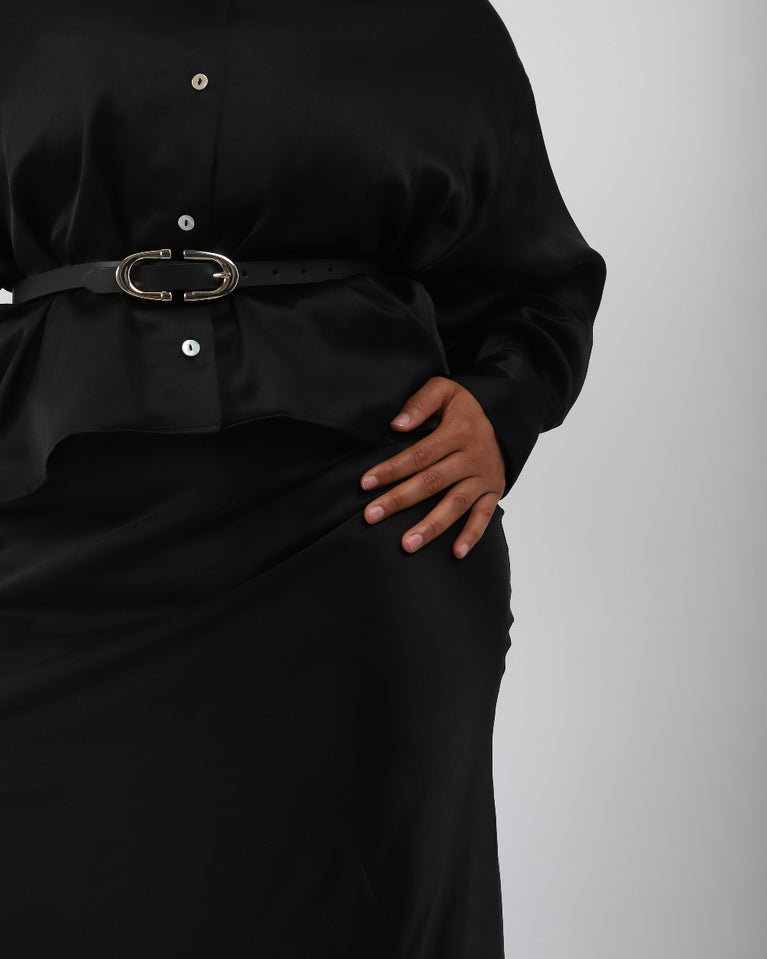 Paradisefold Person wearing a black silk shirt over a black silk slip dress with a silver belt